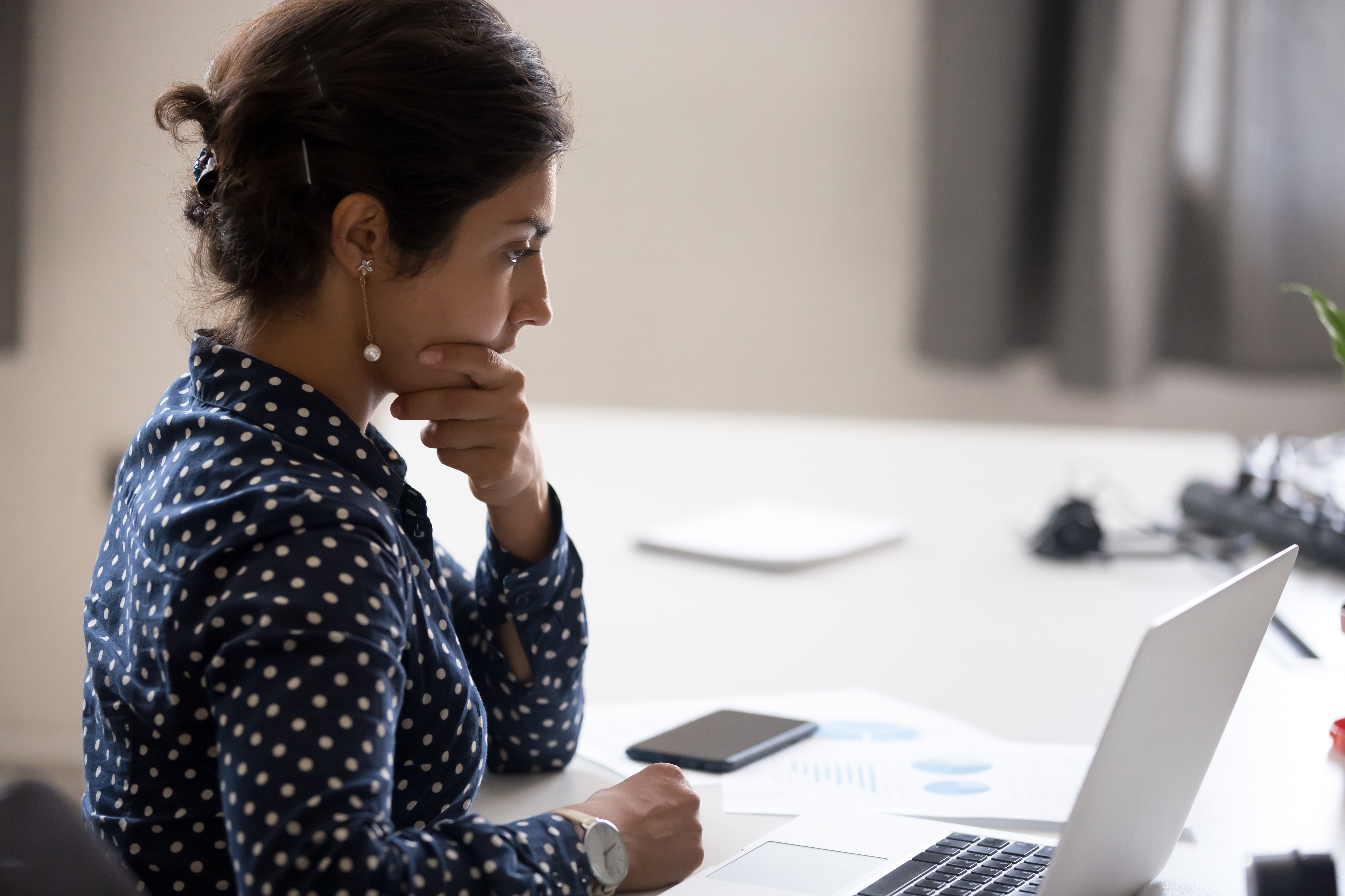 Woman sitting at desk near computer cogitating thinking making important decision at workplace.